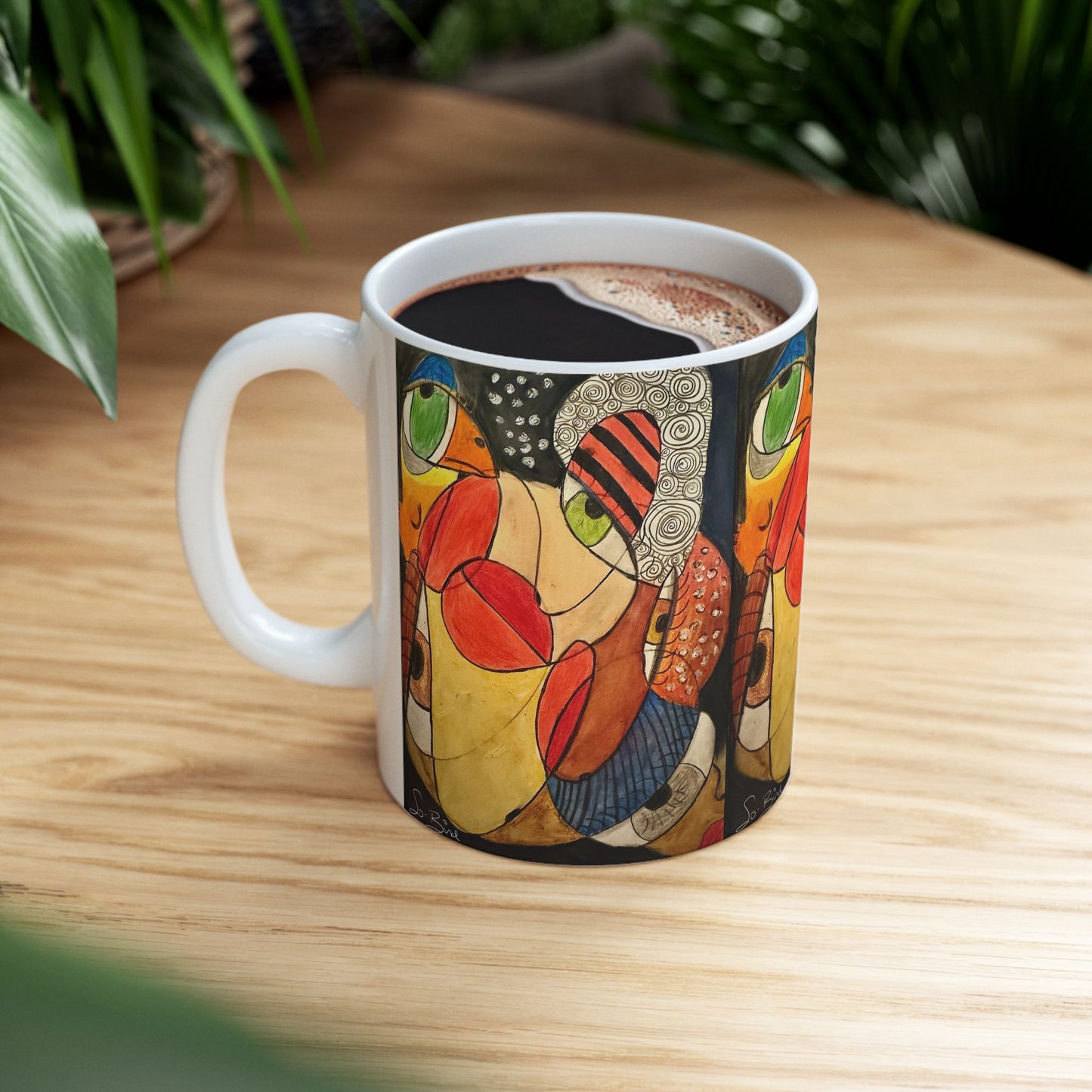 The "Ceramic Mug - It's a WE thing Recovery and Sober Gift" by Printify, featuring dishwasher-safe ceramic with colorful abstract geometric art, sits filled with hot chocolate on a wooden table amid green plants—a thoughtful sobriety gift.