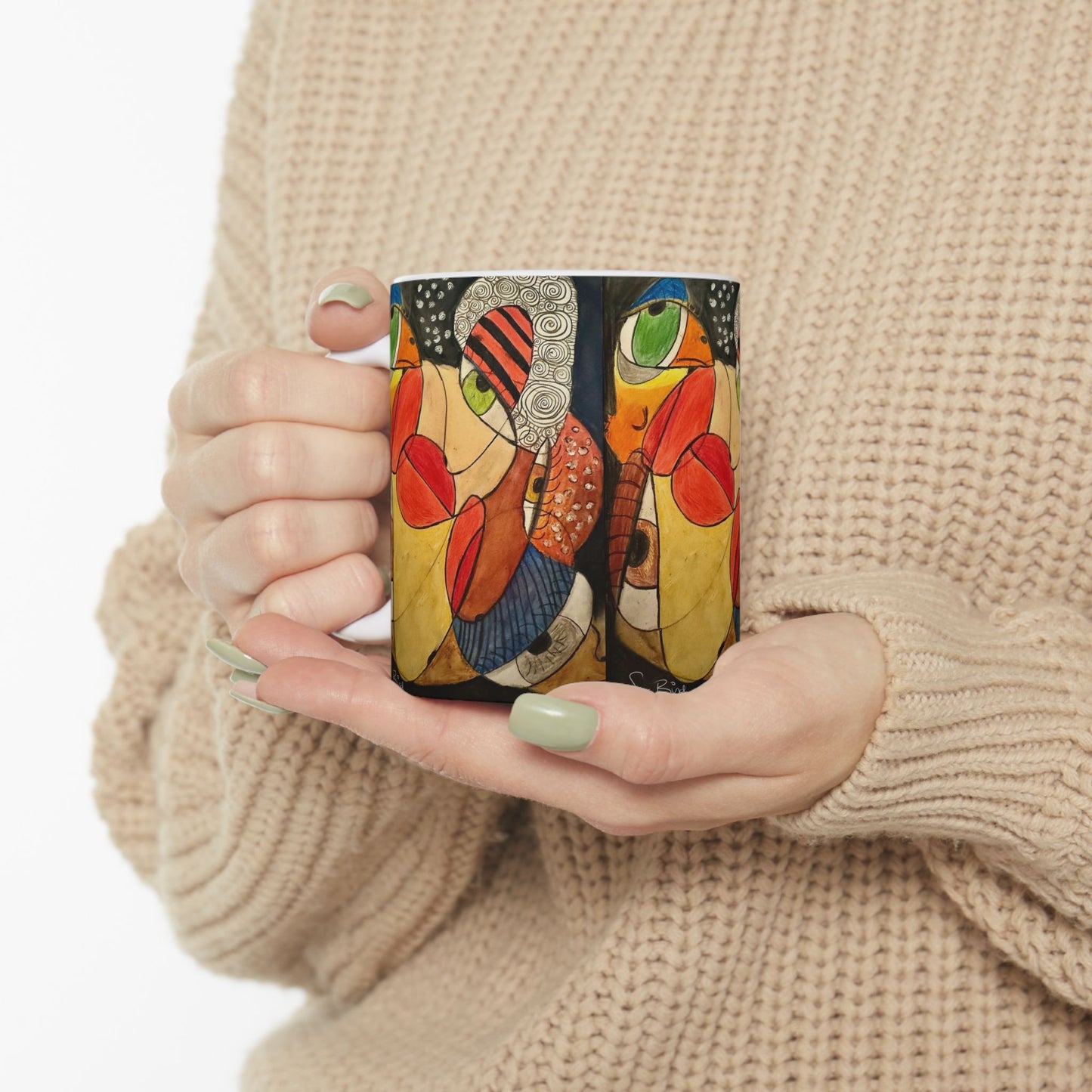 A person in a beige knit sweater holds the Printify "Ceramic Mug - It's a WE thing Recovery and Sober Gift," decorated with colorful abstract art—a vibrant, bold-toned mug perfect as a sobriety gift.