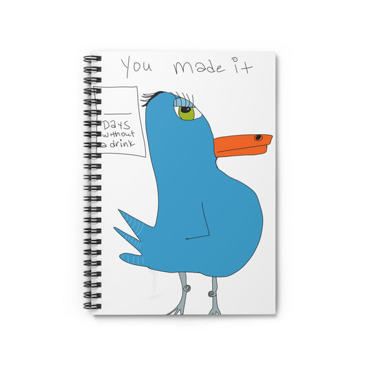 The Recovery Celebration Spiraled Notebook by Printify features ruled lines and a cartoon blue bird with an orange beak beside a "DAYS without drink" sign, with "You made it." handwritten above.